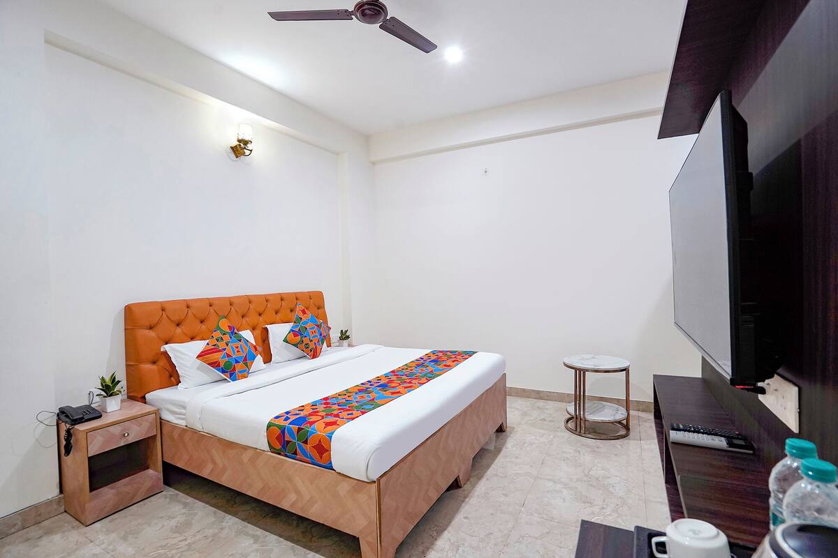 A bedroom with a bed, a nightstand, a small table, a television, and a ceiling fan.