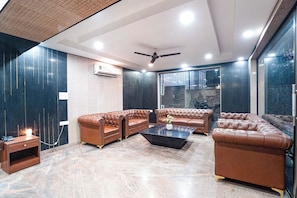 A modern living room with leather sofas, a coffee table, and a ceiling fan. - Fabhotel Divine & Banquet (Noida)