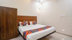 Un dormitorio con un armario de madera, una cama con ropa de cama colorida y una lámpara colgante.