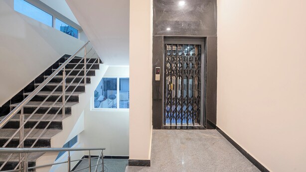 Un interior moderno con una escalera, una puerta de metal y vistas al exterior a través de un ventanal.