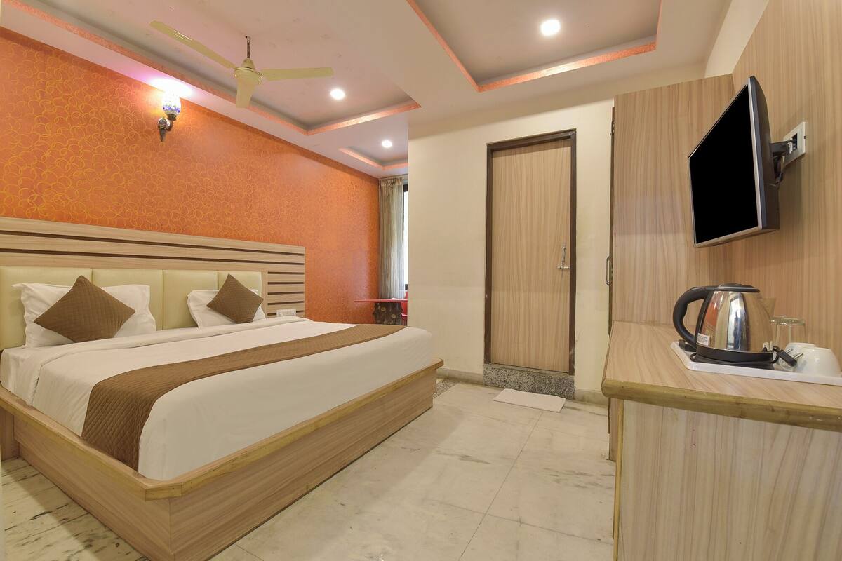 Une chambre d’hôtel équipée d’un lit, d’un téléviseur fixé au mur, d’une bouilloire et d’un bureau en bois.