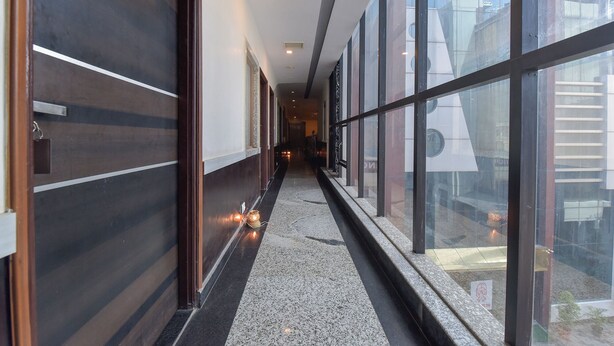 A corridor with a polished floor, wooden paneling on one side, and large windows on the other. - Fabhotel Prime Airport View (Jaipur)