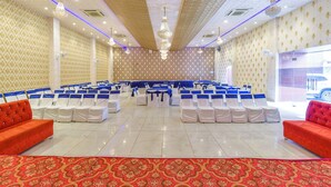 A conference room with rows of white chairs, blue sashes, and red sofas. - Fabhotel Prime Airport View (Jaipur)