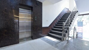 A modern elevator with a digital display, a staircase with metal railings, and a marble floor. - Fabhotel Prime Airport View (Jaipur)