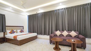 A hotel room with a bed, a sofa, two side tables, and a ceiling fan. - FabHotel Airport Stay Inn - Near Kempegowda Airport (Bangalore)