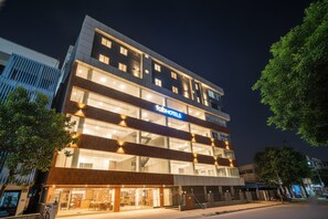 Um hotel de vários andares com um destaque para a placa 'Fachhotels', grandes janelas e um design arquitetônico moderno.