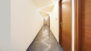 A long, narrow hallway with a polished black floor and wooden doors on one side. - FabHotel Airport Stay Inn - Near Kempegowda Airport (Bangalore)