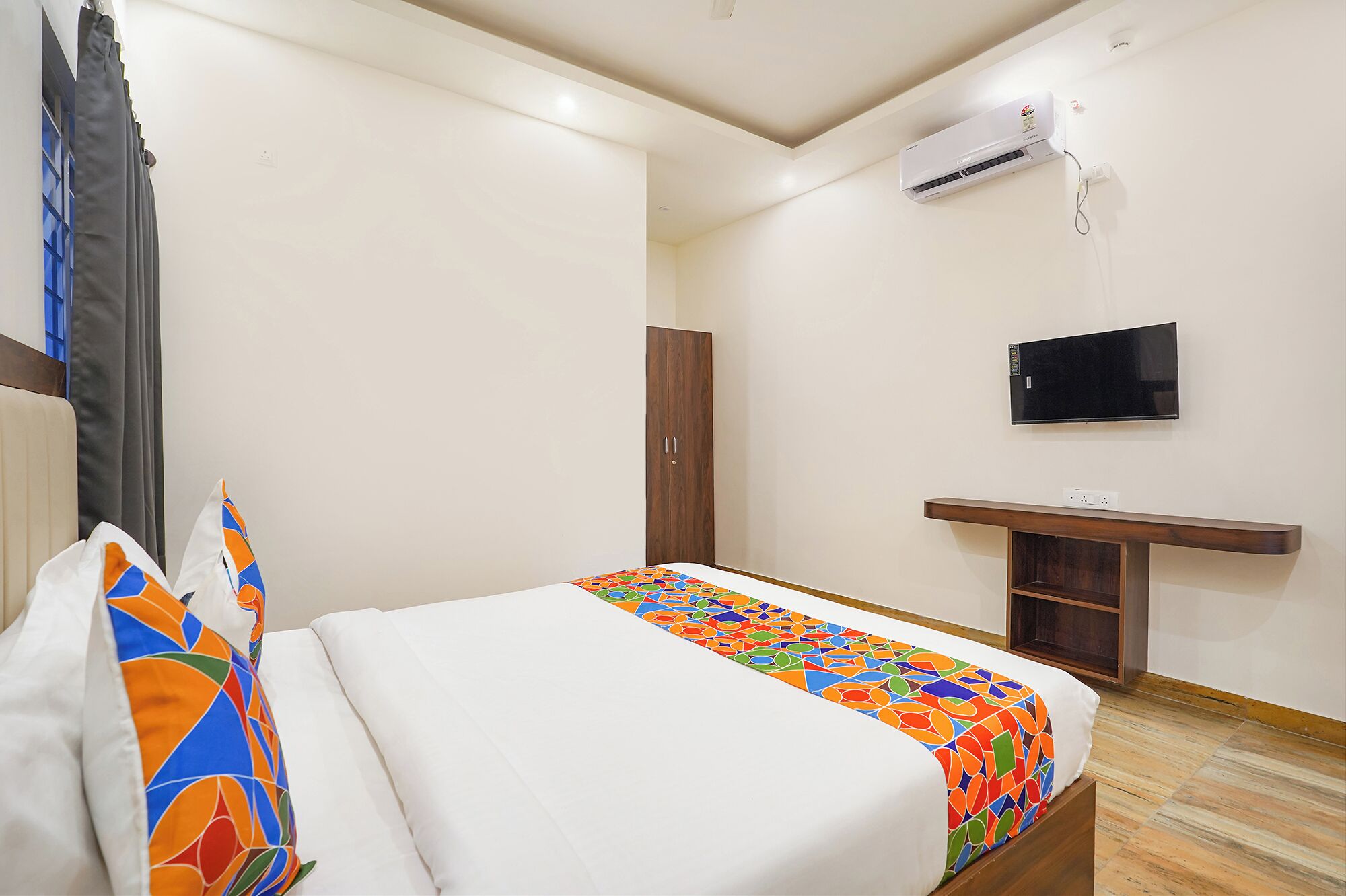 A bedroom with a bed, a wardrobe, a TV, and an air conditioning unit.