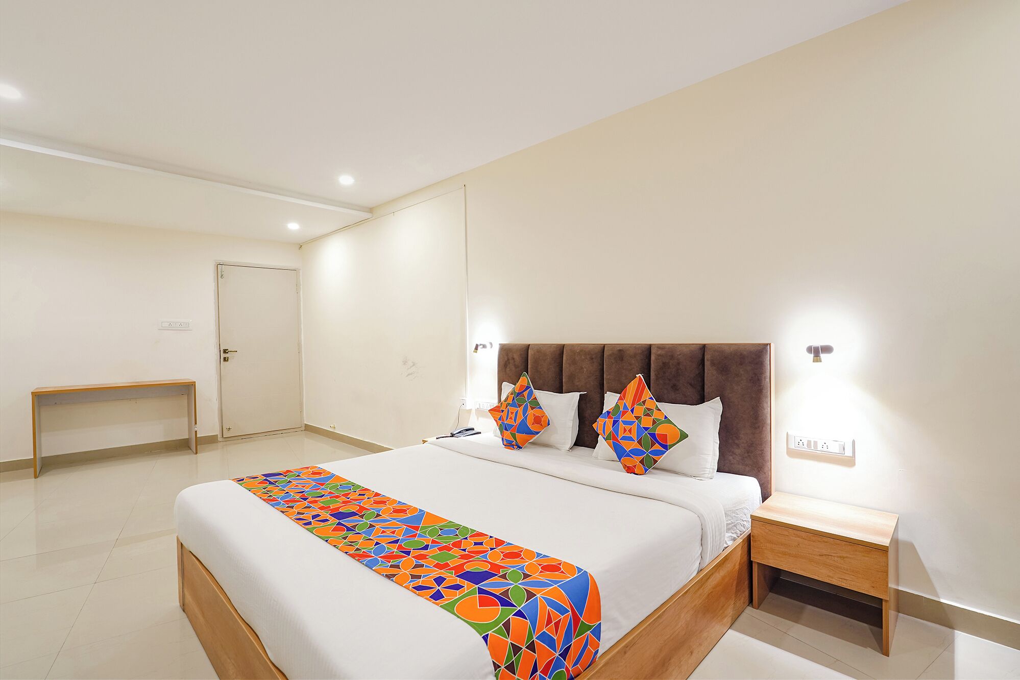 A modern hotel room with a large bed, a bedside table, and a nightstand.