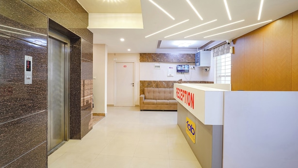 A hotel reception area with a reception desk, a couch, and an elevator. - FabHotel Indian Suites - Krishnarajapuram (Bangalore)
