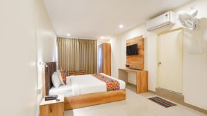 A hotel room with a bed, bedside table, TV, air conditioning unit, and a wardrobe. - FabHotel Indian Suites - Krishnarajapuram (Bangalore)