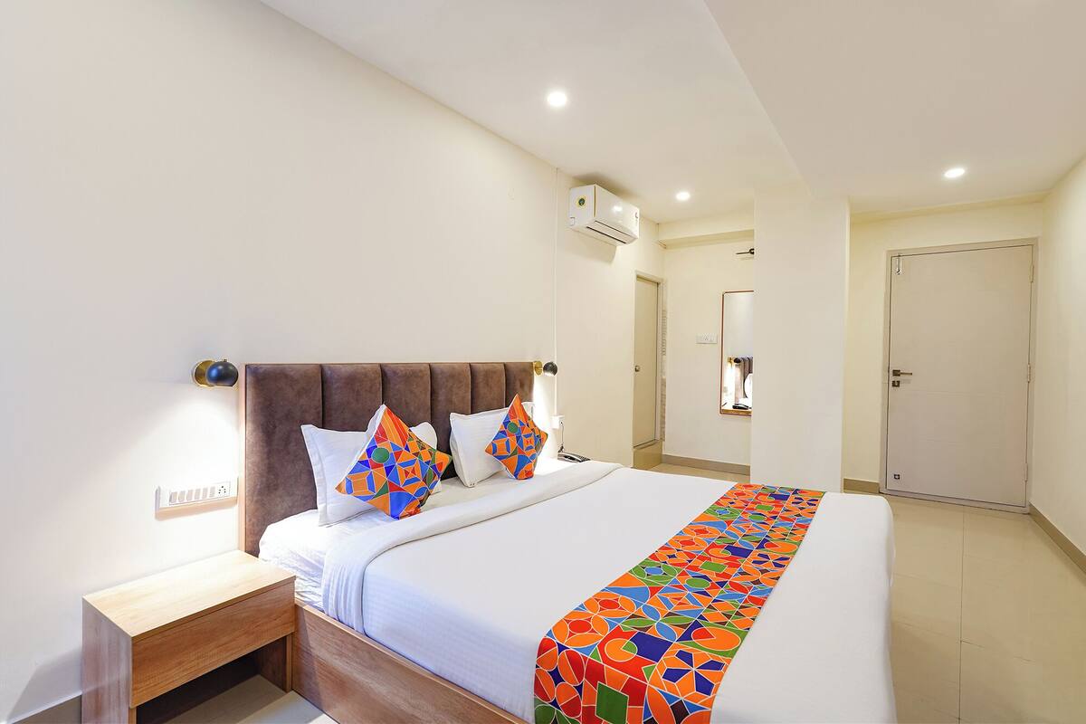 A hotel room with a bed, bedside table, and a nightstand.