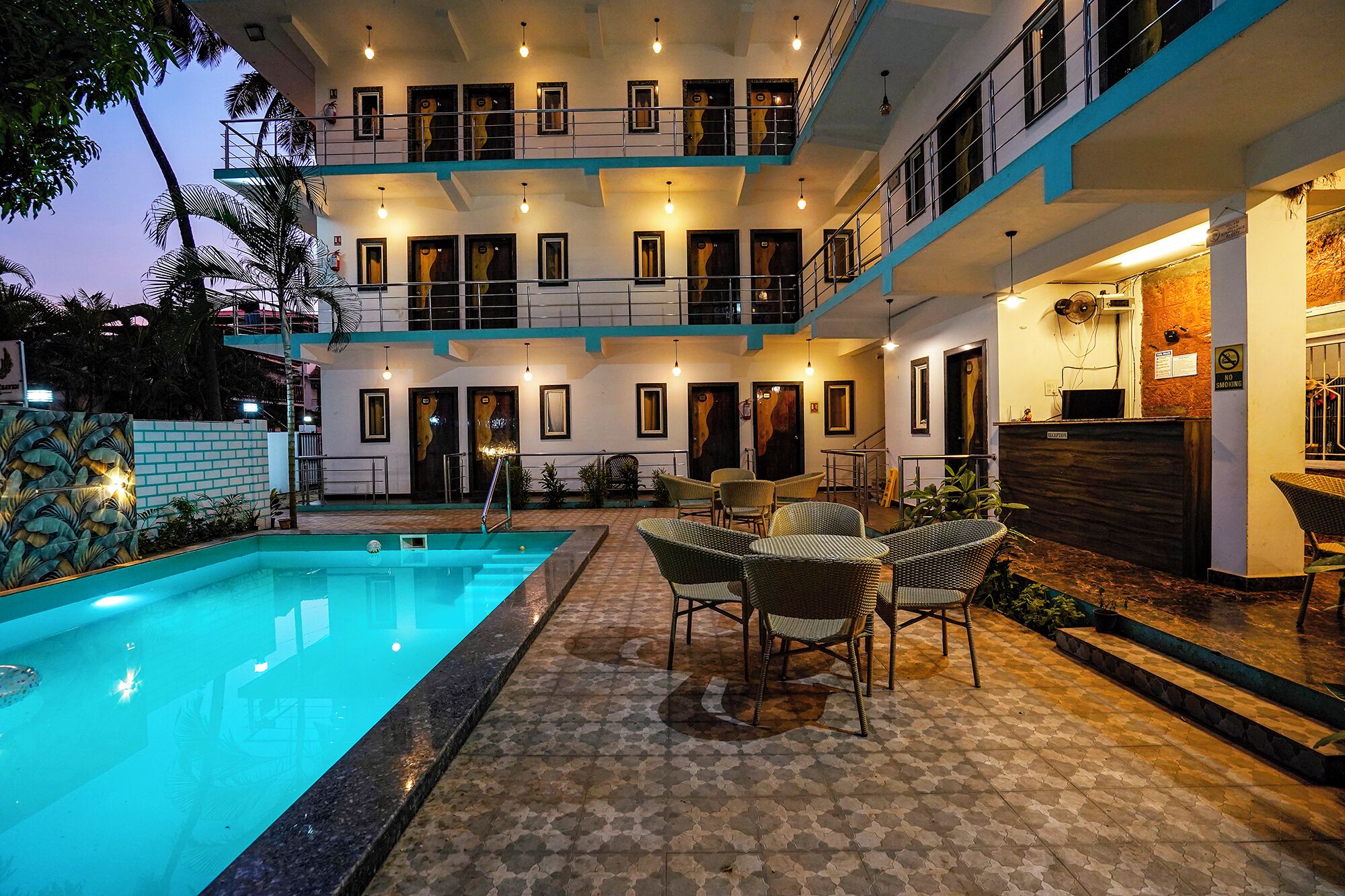 A multi-story building with a swimming pool, outdoor seating, and a reception area.