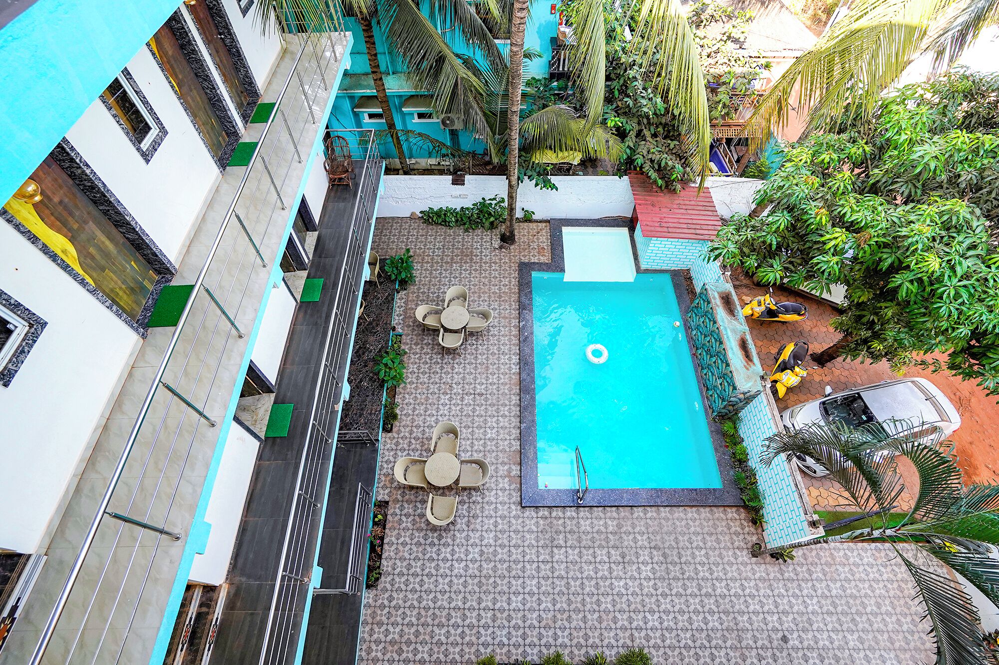 A rooftop pool area with a blue pool, surrounded by lounge chairs and a small seating area.