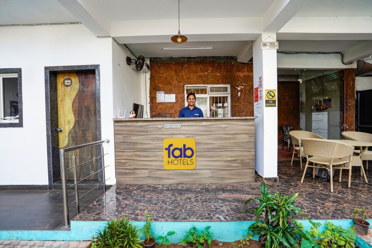 Una recepción con un cartel de 'fab hotels', una puerta de madera, una escalera y un área de descanso con mobiliario de mimbre.