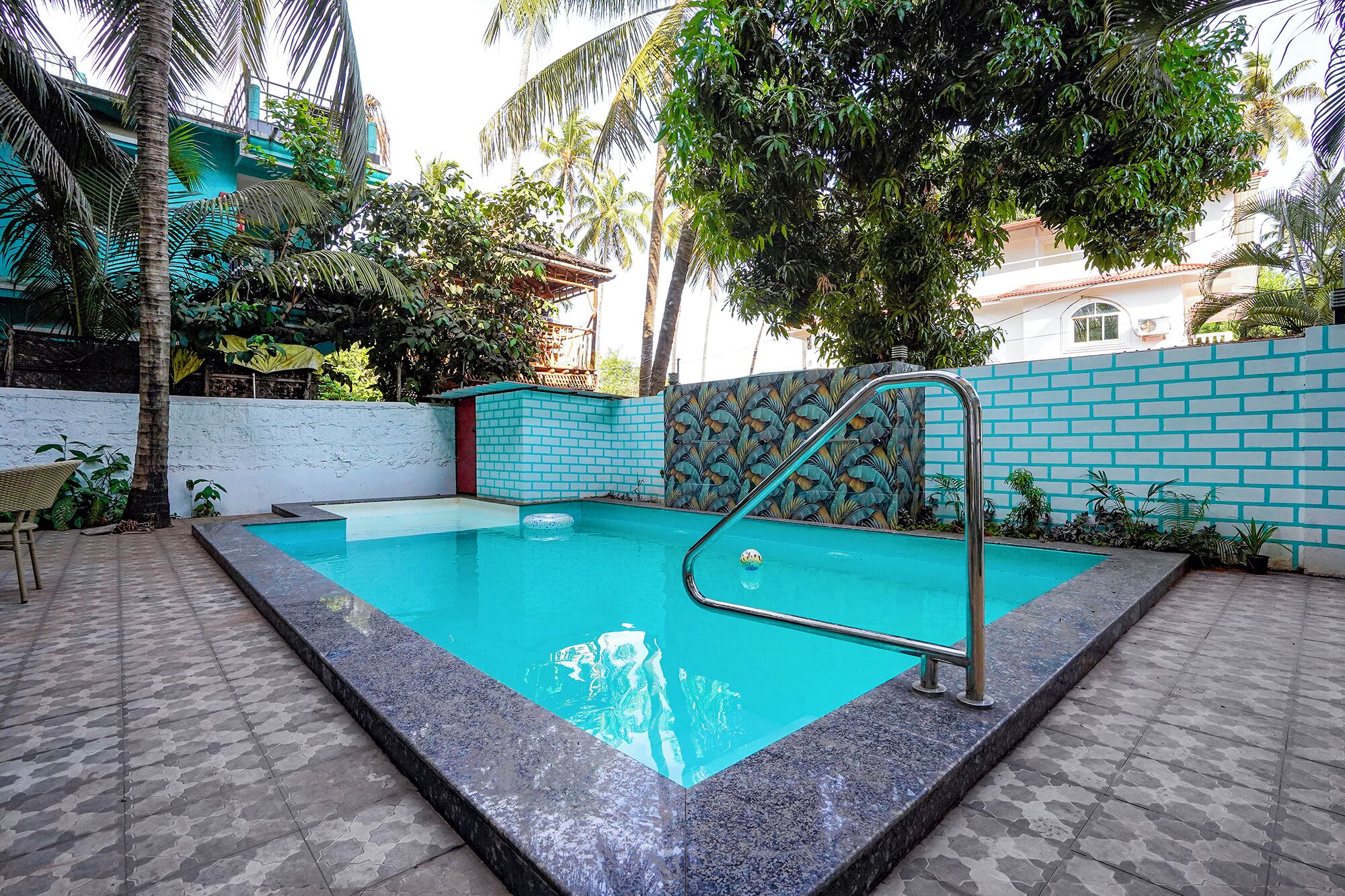 A swimming pool with a tiled deck, surrounded by a low wall with a decorative pattern.