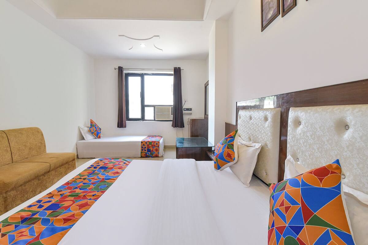A hotel room with a bed, a sofa, a small table, and a window with curtains.