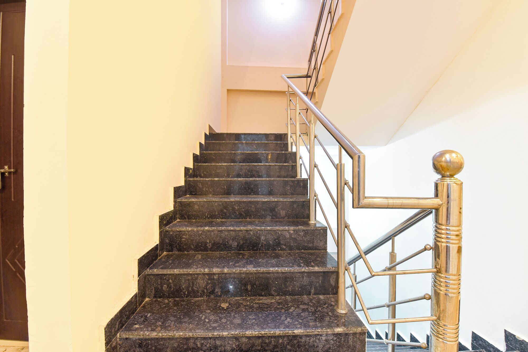 A staircase with dark marble steps and a metal railing with a golden balustrade.