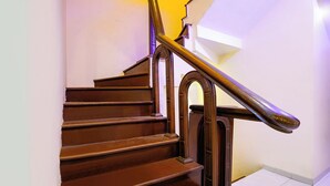 A wooden staircase with a metal handrail and white walls. - Fabhotel Lexus.5 (Mumbai)