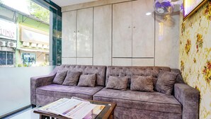 A modern living area with a sofa and a coffee table, a decorative fan, and a patterned wallpaper. - Fabhotel Lexus.5 (Mumbai)