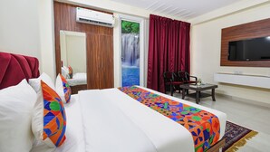 A hotel room with a bed, a desk, a chair, a TV, and a wardrobe. - Fabhotel Trident (New Delhi)