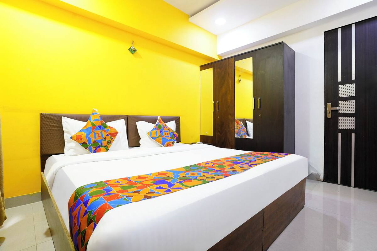 A hotel room with a large bed, a wardrobe, and a mirror.