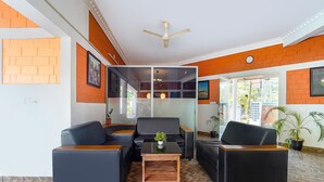 Een moderne lobby met leren banken, een houten salontafel en een plafondventilator.