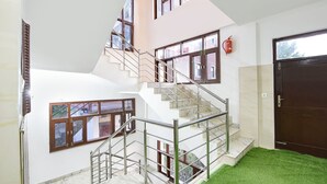 A multi-level interior with a staircase, a fire extinguisher, and a door. - Fabhotel Sn Resort (Dharamshala)