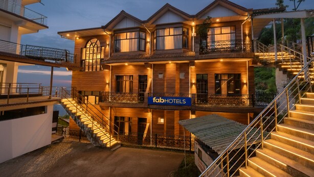 A multi-story hotel with a prominent 'fabHOTELS' sign, featuring balconies, a staircase, and a view of the surrounding area. - Fabhotel Sn Resort (Dharamshala)