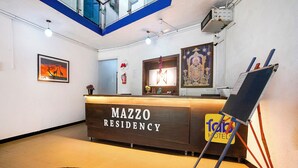 A reception desk labeled "MAZZO RESIDENCY" with a "TOBIS HOTEL" sign, a framed picture, and a fire extinguisher on the wall. - Fabhotel Mazzo Residency (Nagaon)