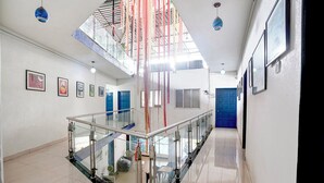 A modern interior with a glass railing, blue doors, and framed artwork on the walls. - Fabhotel Mazzo Residency (Nagaon)