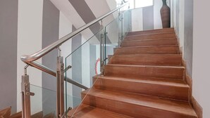 A wooden staircase with glass railings and a metal handrail. - Fabhotel Mazzo Residency (Nagaon)