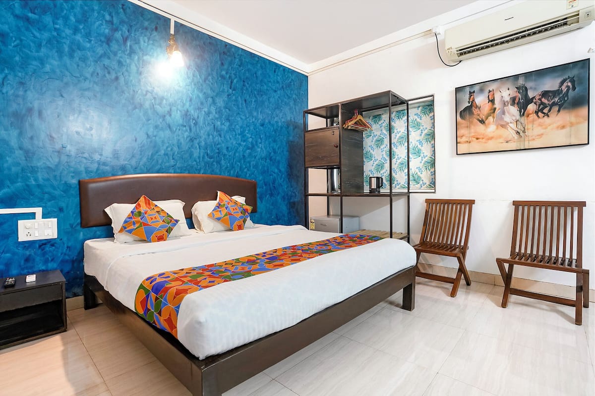 A modern hotel room with a large bed, a nightstand, a desk, and a chair.