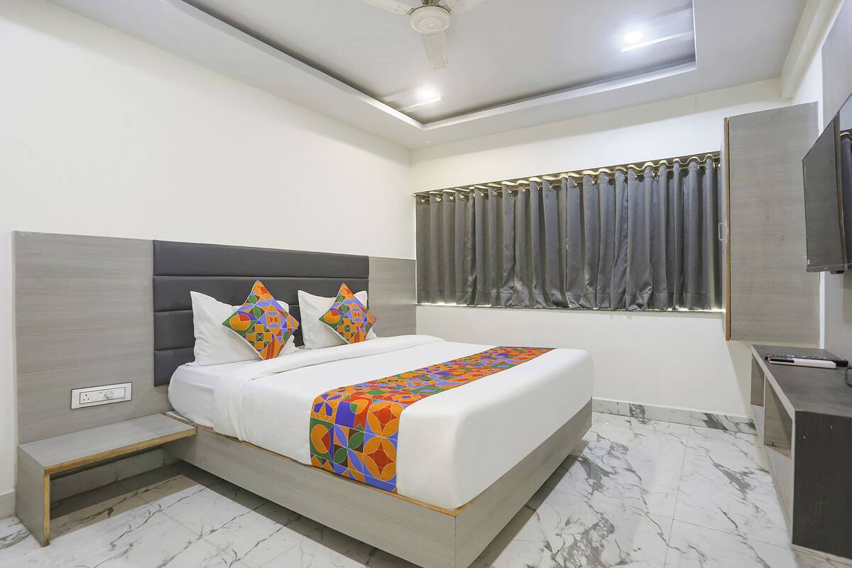 A modern hotel room with a bed, bedside table, and a TV.