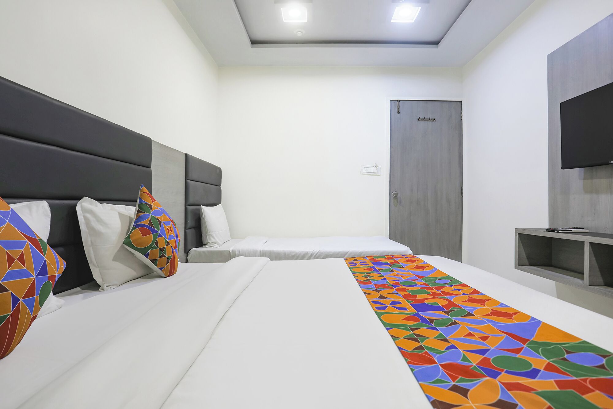 Une chambre d’hôtel avec un lit, une télévision et une porte.