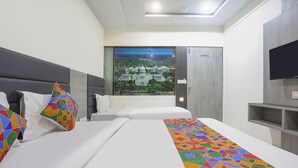 Hotelkamer met twee bedden, een groot raam met uitzicht op de stad, een flatscreen televisie en een modern design.