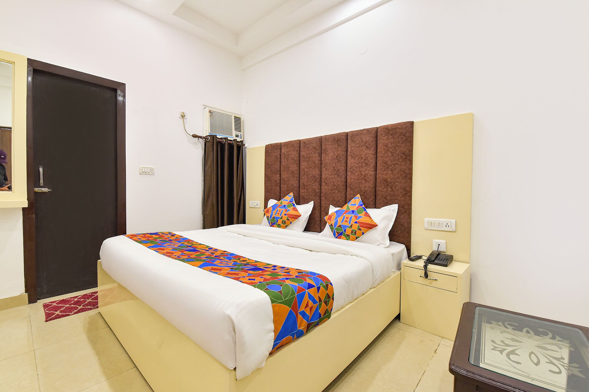 Een verzorgde hotelkamer met een groot bed, een nachtkastje en een deur.