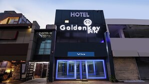 Een hotel genaamd 'Golden Key' met een moderne gevel, een zichtbare ingang en een 'Via'-bord onder het hoofdbord.