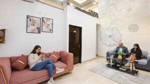 Een moderne lobby met een roze bank, een glazen tafel en een decoratieve wand.