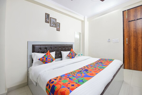 A neatly made bed with a patterned bedspread, a tufted headboard, and two decorative pillows. - Fabhotel The King Residency (New Delhi)