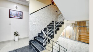 A modern staircase with a white brick wall, metal railings, and a potted plant. - Fabhotel The King Residency (New Delhi)