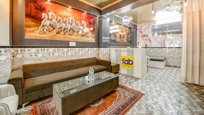 A hotel reception area with a sofa, a glass coffee table, a Buddha statue, and a reception desk. - Fabhotel The King Residency (New Delhi)