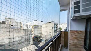A balcony with a view of a residential area, a concrete wall, and an air conditioning unit. - Fabhotel The King Residency (New Delhi)