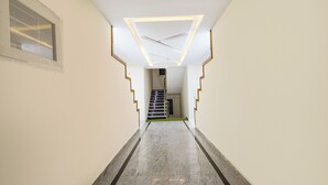 A modern hallway with a geometric light fixture, a staircase, and a door at the end. - Fabhotel Navya Grand (Hyderabad)
