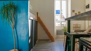 A modern interior with a blue accent wall, a wooden staircase, and a bar area with stools. - Charming Studio for 2/4 Guests – City Center (Les Sables-d´Olonne)