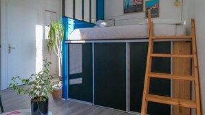 A room with a bunk bed, a potted plant, a ladder, and a wall with framed pictures. - Charming Studio for 2/4 Guests – City Center (Les Sables-d´Olonne)