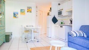 A compact living space with a dining area, kitchenette, and a blue sofa.