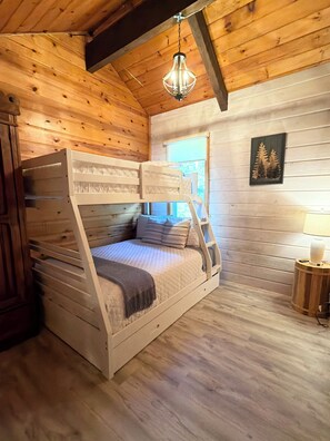 A bunk bed in a wooden room with a hanging light fixture and a framed picture on the wall. - Pondside Haven (Tors Cove)