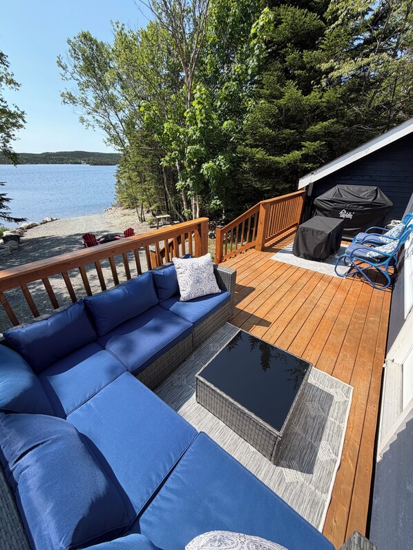 A deck with a blue sofa, a small table, and a grill area.