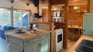 Una cucina accogliente in stile baita, con mobili in legno, piano cottura integrato e zona pranzo con tavolo e sedie.